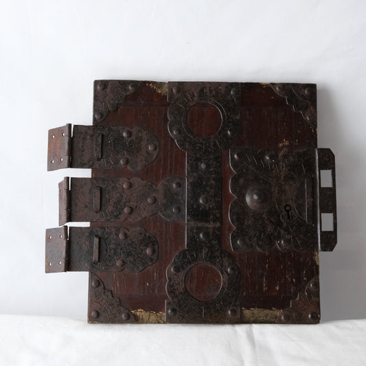 Front of an antique Japanese funa tansu door from Noto with decorative metal fittings and dark wood.