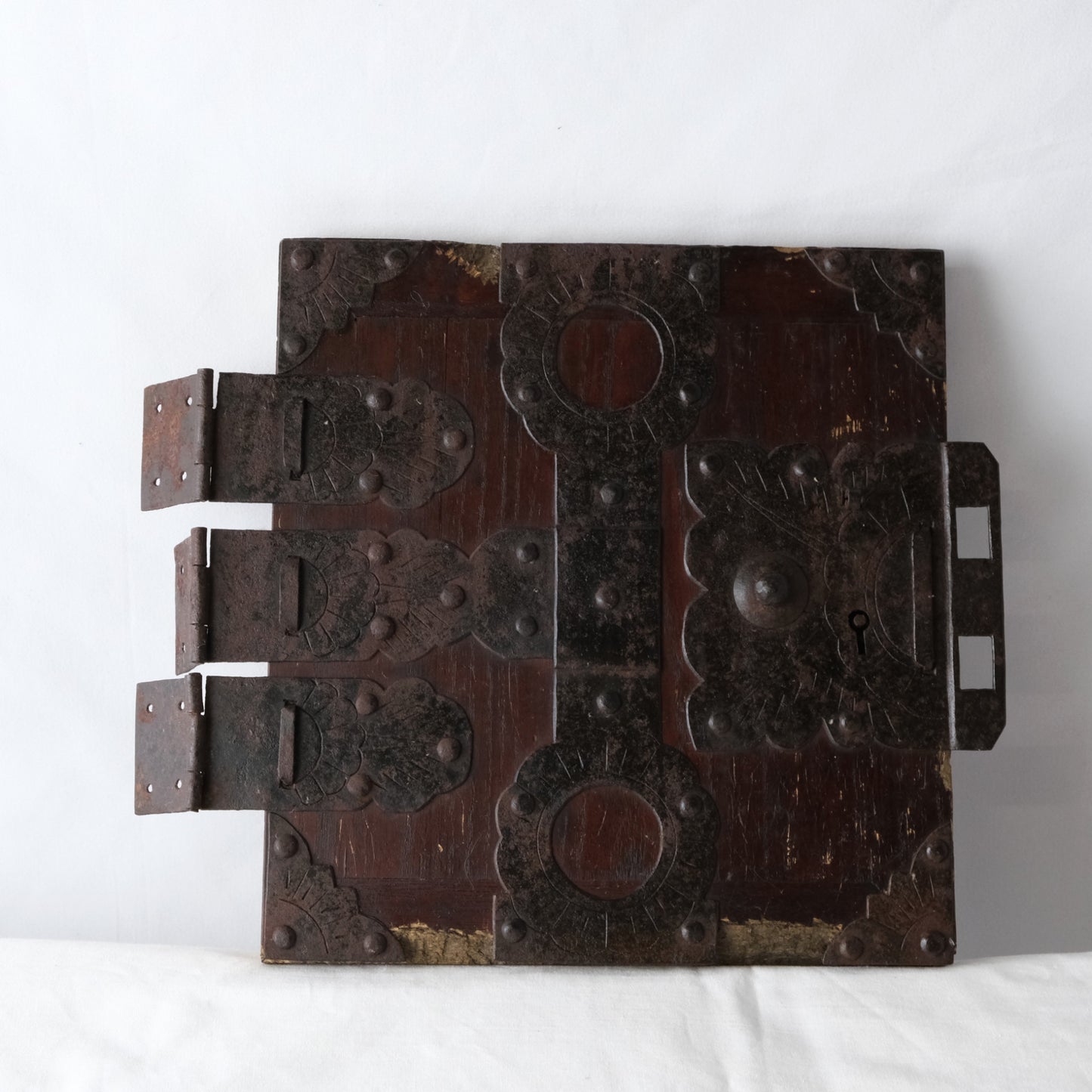 Front of an antique Japanese funa tansu door from Noto with decorative metal fittings and dark wood.